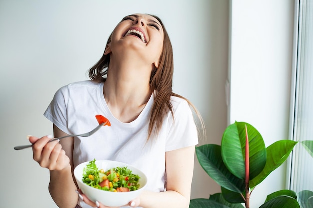 Mulher feliz comendo salada